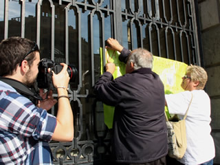 Uns manifestants pengen un cartell contra les retallades a la sanitat a l'entrada de la seu de l'ICS. (Foto: ACN)
